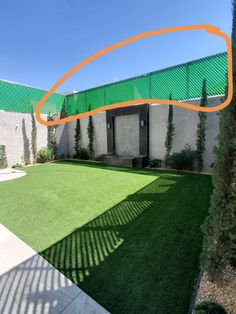 a backyard with artificial grass and an orange circle in the center, on a sunny day