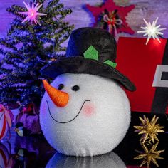 a snowman sitting next to a christmas tree