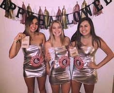 three girls dressed in shiny silver dresses posing for the camera