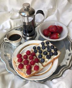 a plate topped with two slices of cake and berries next to a cup of coffee