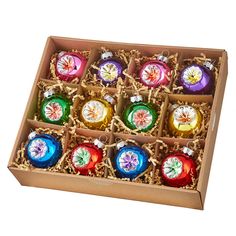 an open box with twelve christmas ornaments in it, on a white background the boxes are filled with different designs and colors