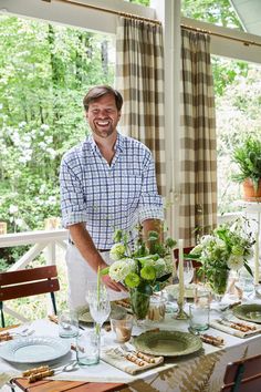 a man standing in front of a table with plates and glasses on top of it