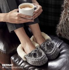 a woman holding a cup of coffee while wearing slippers