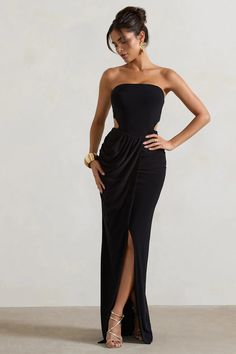 a woman in a strapless black dress poses for the camera with her hands on her hips