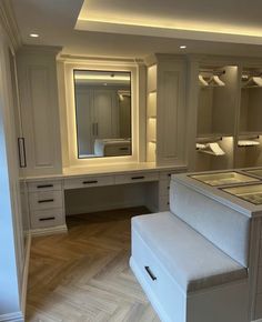 an empty dressing room with white furniture and mirrors on the wall, along with lights