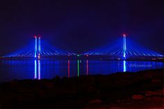 the blue bridge is lit up at night with bright lights on it's sides