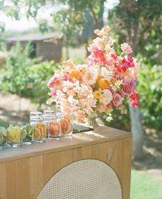 a wooden table topped with vases filled with flowers next to an old radio set