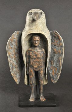 a statue of an angel holding a man's head with wings on top of it