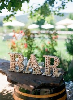 the letters are made out of wine corks and sit on top of a barrel