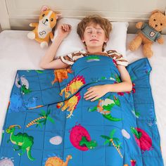 a little boy laying in bed with stuffed animals