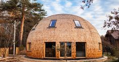 a round wooden building in the middle of a forest