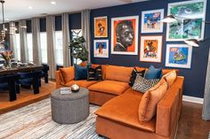 a living room with orange couches and pictures on the wall above it, along with a piano