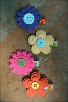 three different colored flowers with buttons on them sitting on the ground next to each other