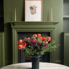 a table with flowers on it in front of a fireplace