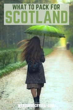 a woman walking down a dirt road holding an umbrella with the words what to pack for scotland