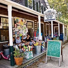 two people sitting on the front porch of a building with an outside sign that says,