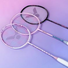 three tennis racquets laying on top of each other in front of a purple background