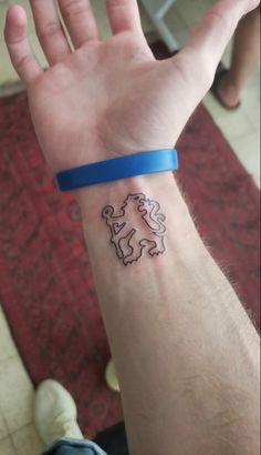 a person's arm with a tattoo on it and a blue band around the wrist