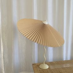 a lamp that is sitting on top of a table next to a white sheet curtain