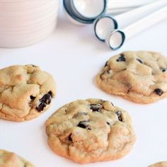 chocolate chip cookies on a white surface next to utensils and a glass of milk