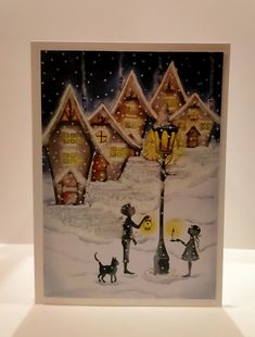 a christmas card with two children and a dog in front of a snowy village at night