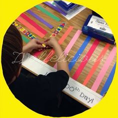 a person sitting at a table with some colorful strips on it and writing on the wall