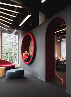 an office with a circular mirror on the wall next to a bench and round ottoman