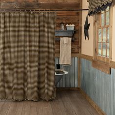 a bathroom with wooden walls and flooring has a checkered shower curtain in the corner