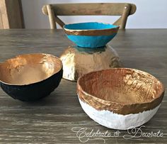 three bowls sitting on top of a wooden table next to each other, one blue and the other gold