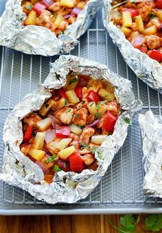 chicken and vegetables wrapped in tin foil on top of a grill with the words win above it