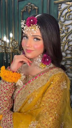 a woman with flowers in her hair wearing a yellow outfit and holding a flower headpiece