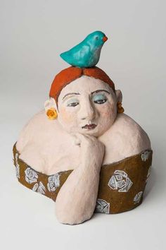 a ceramic sculpture of a woman with a bird on her head