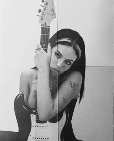 a black and white photo of a woman holding a guitar in front of her face