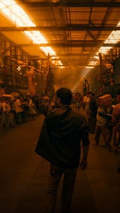 a man is walking down the street in front of an industrial area with lots of people