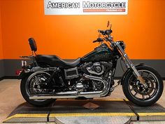 a motorcycle is parked in front of an american motorcycle sign and orange wall behind it