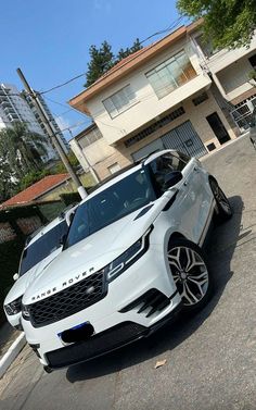 two white cars parked in front of a building on the side of a road next to another car