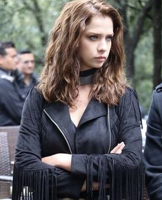 a woman with her arms crossed wearing a leather jacket