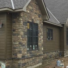 a house that is being built with stone and shingles on the side of it