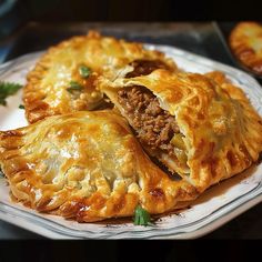 some meat and cheese pastries on a white plate