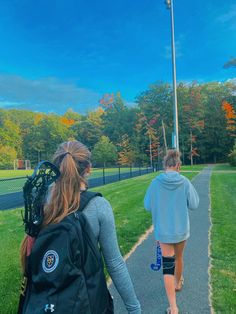 two people walking down a path with backpacks