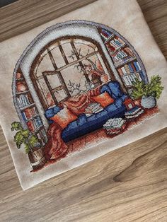 a cross stitched picture of a couch in front of an open window