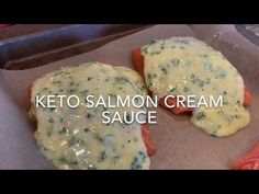 two pieces of salmon covered in cheese on top of a baking sheet with the words keto salmon cream sauce