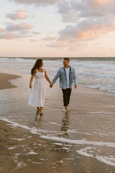 a man and woman walking on the beach holding hands