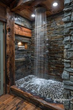 a shower head in the corner of a room with wood flooring and stone walls