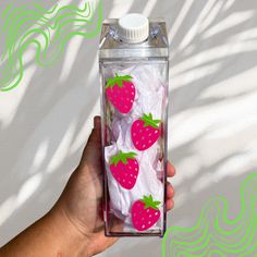 a hand holding a plastic bottle with strawberries on it and tissue paper in the bottom