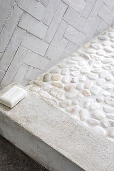 a white toilet sitting on top of a stone floor next to a bathtub covered in pebbles