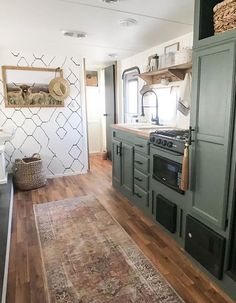 a kitchen with green cabinets and an area rug on the floor in front of it