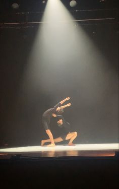 two dancers performing on stage in front of spotlights