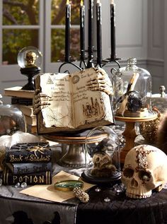 a table topped with lots of books and skulls on top of eachother filled with candles