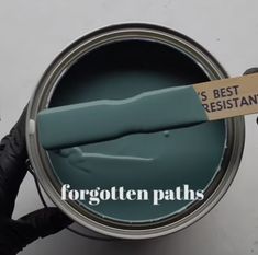 a person holding a paint can with the words forgotten paths painted on it